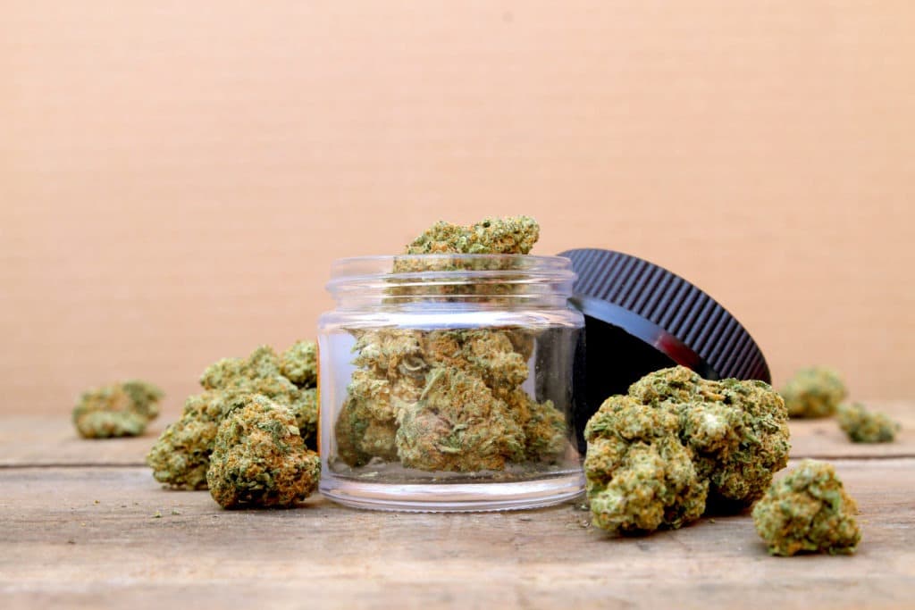Marijuana in Open Jar Surrounded by Buds.