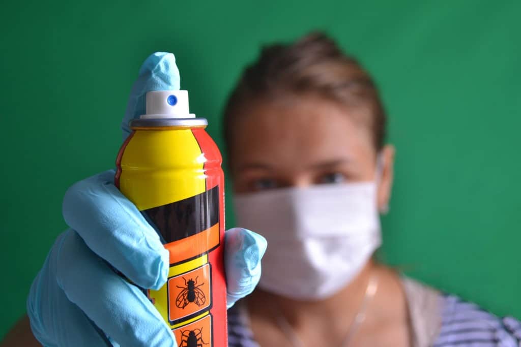 Woman with mask holding insect spray.