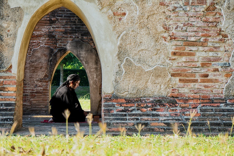 Old muslim male praying with koran in old mosque.