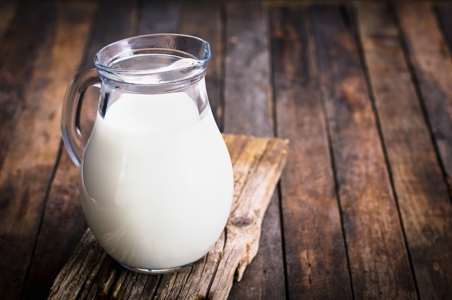 Fresh milk in the jug on a wooden table.