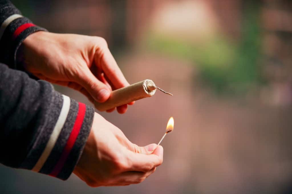 Hand lighting up a firecracker.