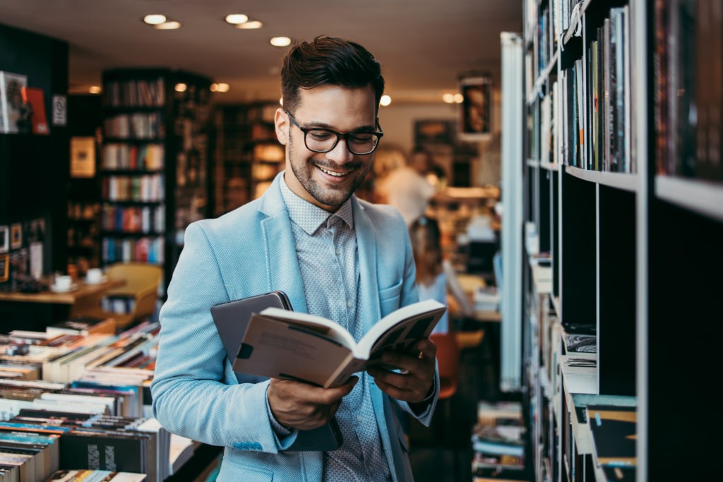 Man choosing and reading books at a bookstore.